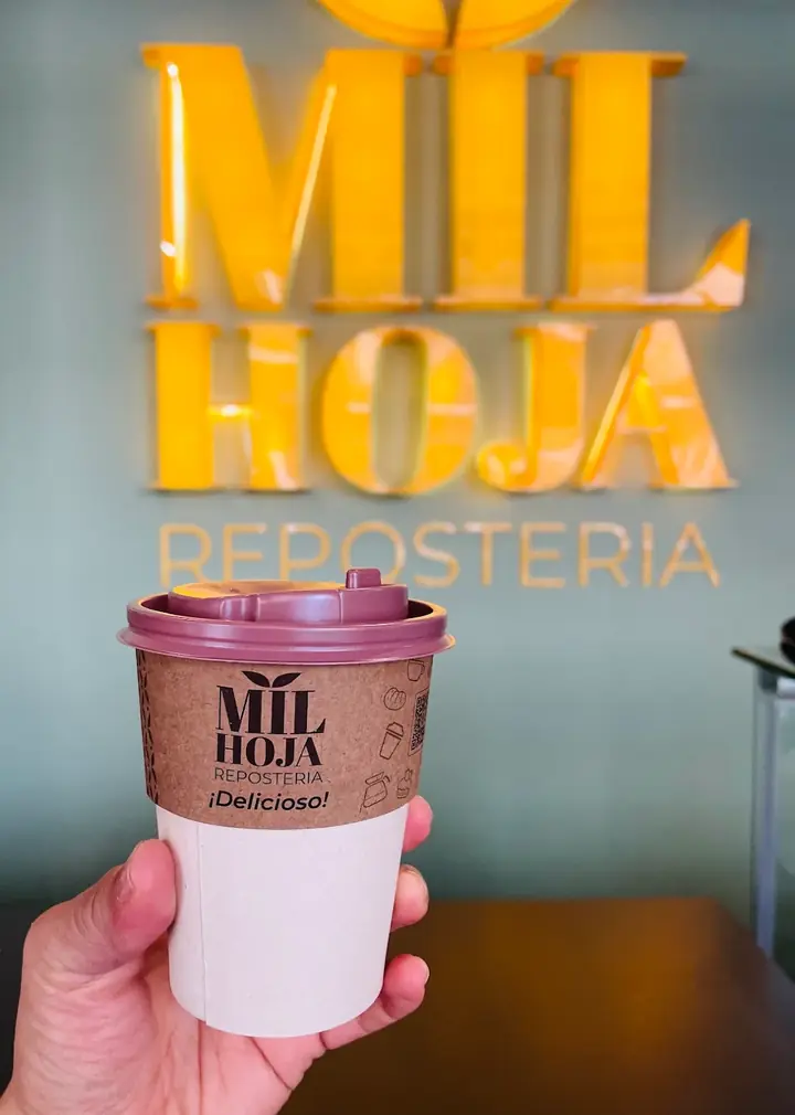 Café para llevar frente al aviso de Milhoja Repostería